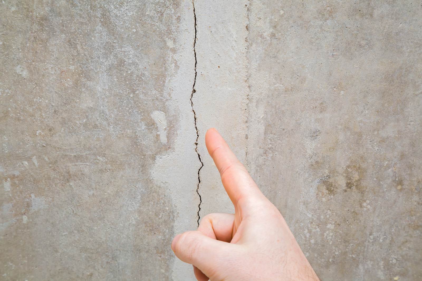 stucco cracks home inspection Chicago hand pointing at wall